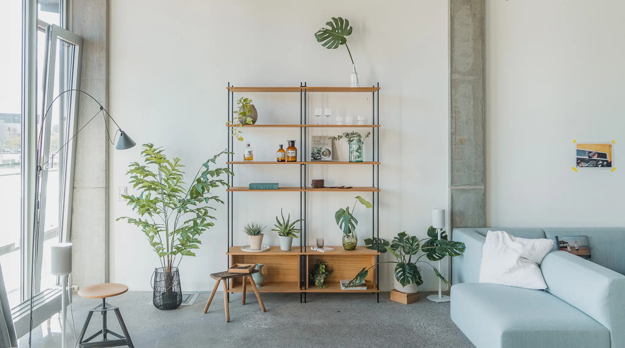 Loft-Wohnzimmer mit zweisektioniger KUUDU-Standing-Konfiguration, Pflanzen und Vasen auf Ebenen, links Stehlampe Anglepoise, rechts mintgrünes Sofa
